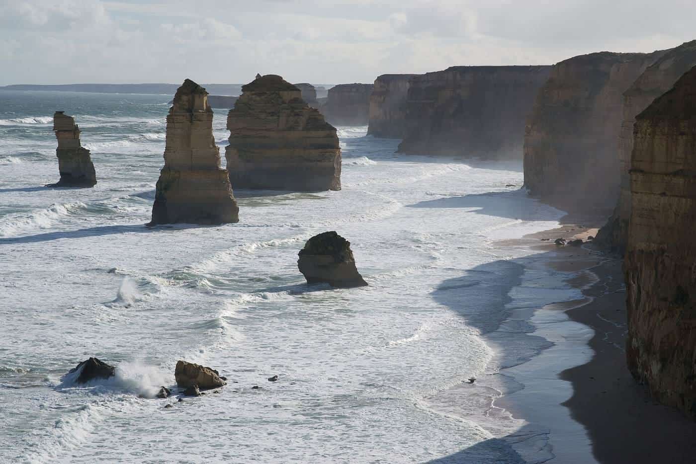 The Twelve Apostles limestone stacks along a rugged coastline at sunset